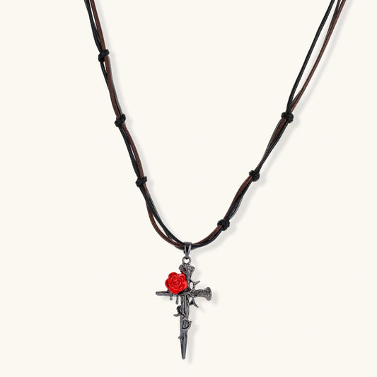 Gothic cross pendant with red enamel rose and thorn details on adjustable brown cord necklace against white background.